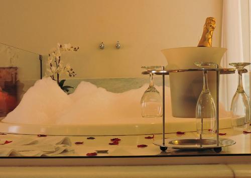 a bath tub with two wine glasses and flowers on it at Pousada Ouro de Minas in Tiradentes
