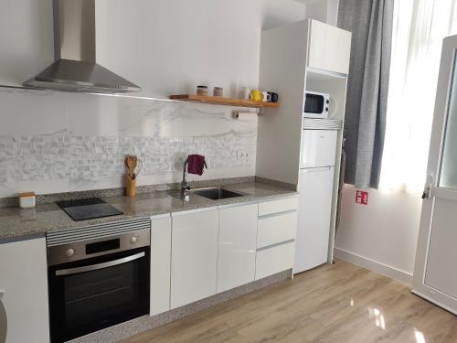 a white kitchen with a sink and a stove at apartamentos YEIK in Muxia