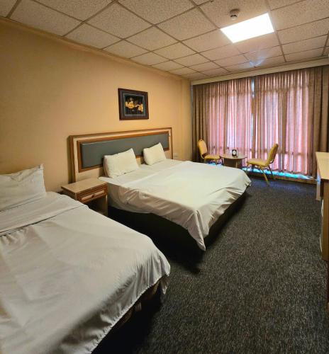a hotel room with two beds and a window at HERSH Palace Hotel in Erbil