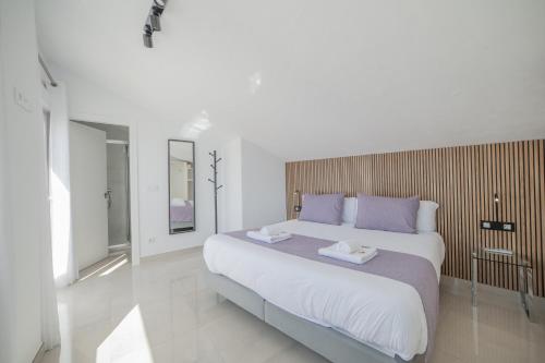 a white bedroom with a large bed with purple pillows at Principado de Aracena I in Aracena