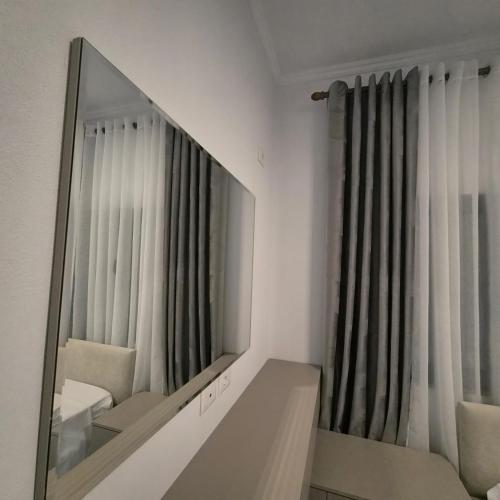 a mirror in the corner of a room with a chair and a couch at Kypsel Apartment in Durrës