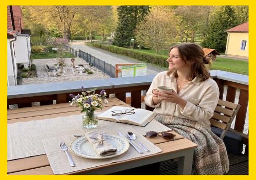 a woman sitting at a table with a glass of wine at Ferienwohnung Auszeit am Kurpark Bad Berka # Balkon # ruhige Lage # gratis Parkplatz & WLAN # Weimarer Land # nahe Weimar & Erfurt in Bad Berka