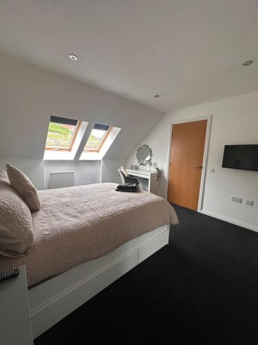 a bedroom with a bed and two windows and a television at 6 Pegasus Place in Lerwick