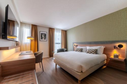 a hotel room with a bed and a desk at Holiday Inn Mulhouse by IHG in Mulhouse