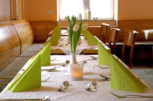 uma mesa longa com cadeiras verdes e flores em Goldener Schlüssel mit Gästehaus Sina em Nördlingen