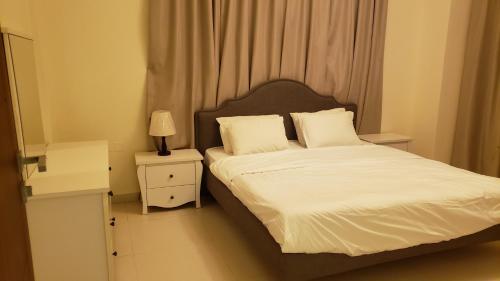 a bedroom with a bed with white sheets and pillows at Alzahraa apartment in Salalah