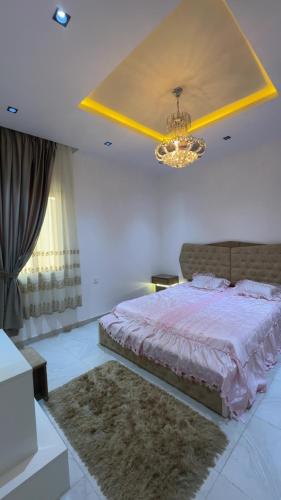 a bedroom with a large bed and a chandelier at أستراحة الهوني in Banghāzī