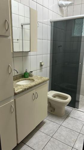 a bathroom with a toilet and a sink and a mirror at Casa Aconchegante com 2 quartos in Araçariguama