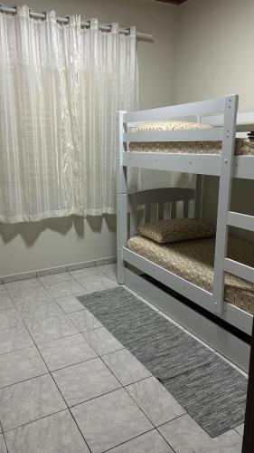 a bedroom with a white bunk bed and a window at Casa Aconchegante com 2 quartos in Araçariguama