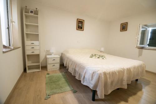 a white bedroom with a bed and a shelf at APARTMA BrdonKA in Dobrovo