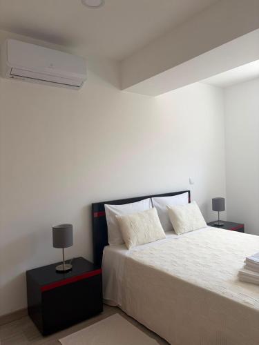 a bedroom with a large white bed with two lamps at Alojamento das cantarinhas in Bragança