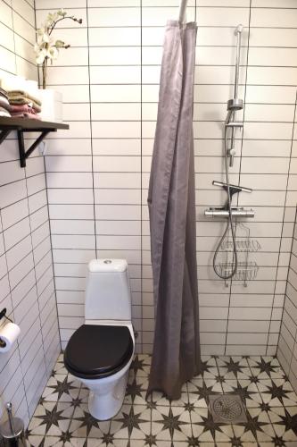 a bathroom with a black toilet and a shower at B&B Olsegården in Tvååker