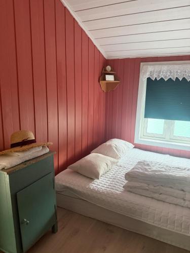 a bedroom with a red wall with a bed and a window at Vetleberget - simple living in Vaga