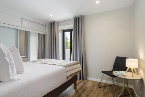 a bedroom with a bed and a chair and a window at Oceanea Apartment by Homie in Santa Cruz