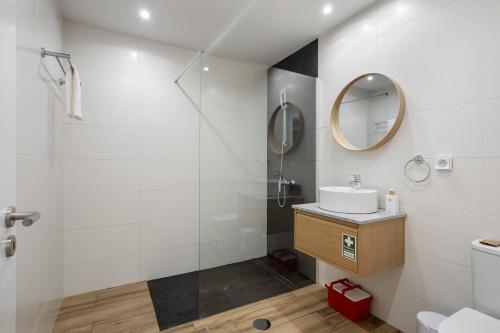 a bathroom with a shower and a sink and a mirror at Oceanea Apartment by Homie in Santa Cruz