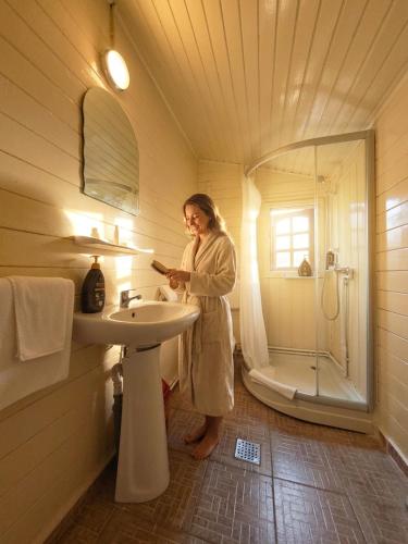 a woman standing in a bathroom with a sink and a shower at Mara by iVAVev in Eforie Sud