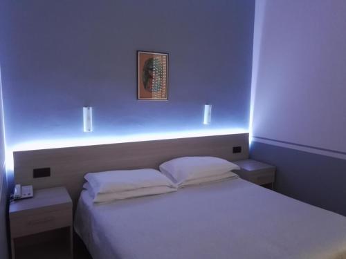 a small bedroom with a white bed with lights on it at Hotel Astoria in Tabiano