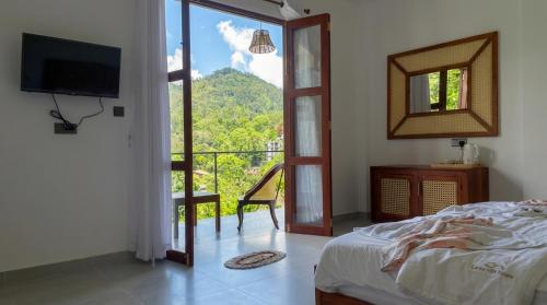 a bedroom with a bed and a view of a balcony at Ceylon tea resort Ella in Ella