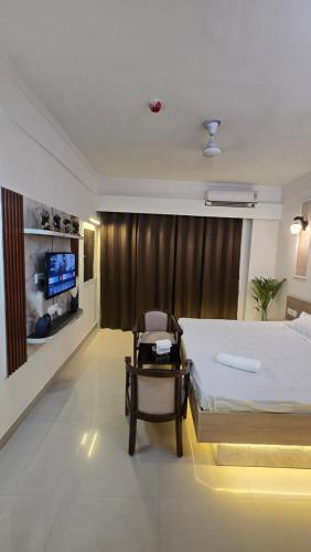 a bedroom with a bed and a chair and a tv at Modern Studio With Balcony & Raod Facing View in Noida