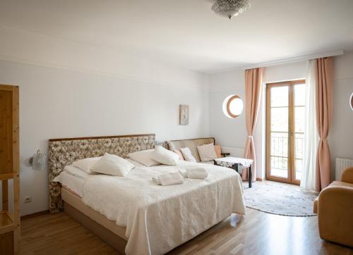 a white bedroom with a large bed and a couch at Dworek Biesiadny in Radzewice