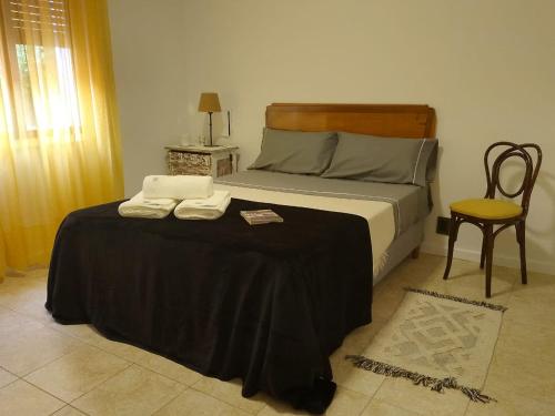a bedroom with a bed with a black blanket and a chair at Petit Margaret in Santa Rosa