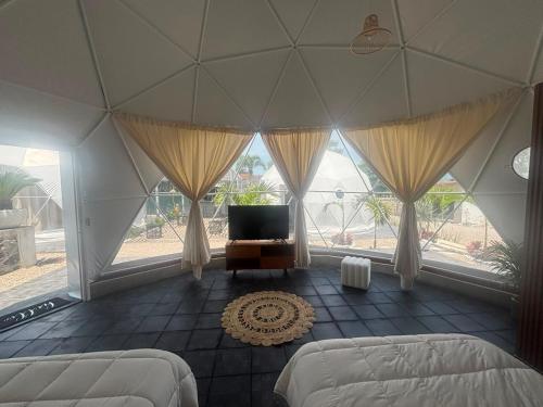 a room with two beds and a tv and windows at Lol-ha glamp in Temixco