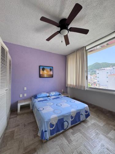 a bedroom with a bed with a ceiling fan at Tiki’s Penth in Acapulco