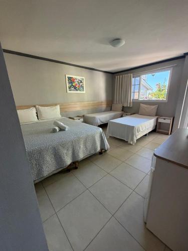 a hotel room with two beds and a window at Pousada Pérola do Mar in Tamandaré