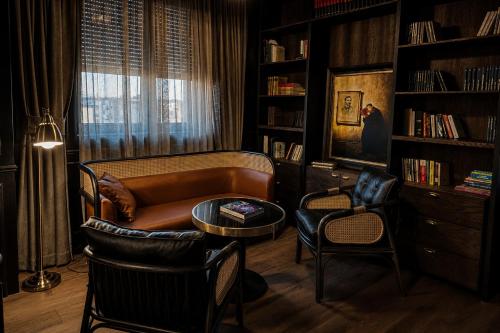 a living room with a couch and chairs and bookshelves at Lusso Hotel in Prishtinë
