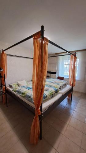 a bed with an orange canopy in a room at Mecseki Farkasvár in Magyarhertelend
