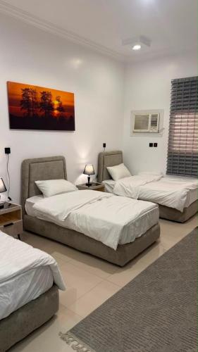a room with three beds and a painting on the wall at Sweet Sbah in Hail