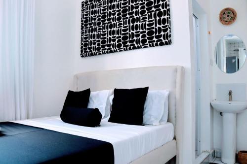 a bedroom with a white bed with black pillows at Soft stay homes in Mombasa