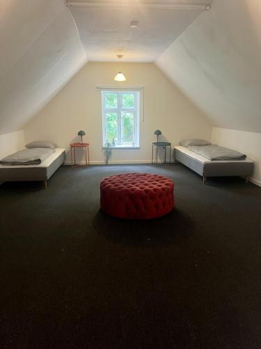 a room with two beds and a red ottoman at The Blue Country House in Nørre Broby