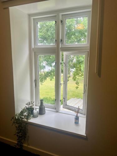 an open window with vases on a white window sill at The Blue Country House in Nørre Broby