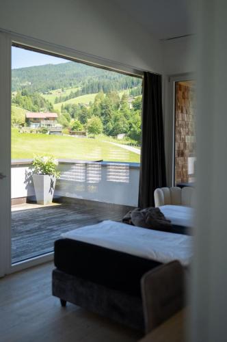 a bedroom with two beds and a large window at ALMMONTE LIGNUM - Premium Lodge in Wagrain