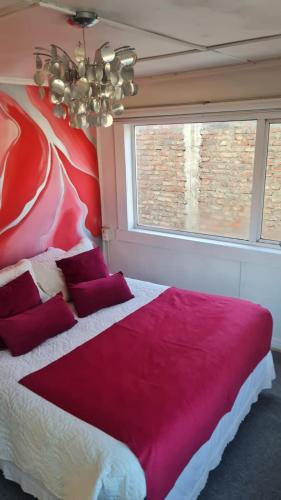 a bedroom with a large bed with red pillows at Hostal Posada Lupinos in Punta Arenas