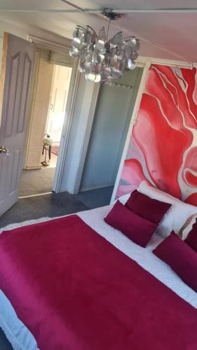 a bedroom with a red and white bed with red pillows at Hostal Posada Lupinos in Punta Arenas