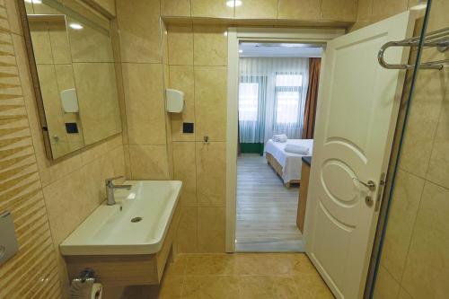 a bathroom with a sink and a mirror and a bed at Doruk Pansiyon in Amasra