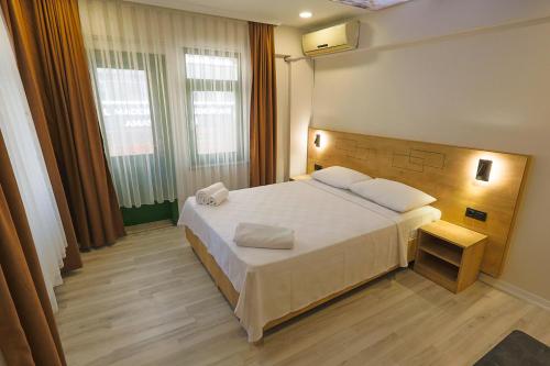 a bedroom with a large white bed and two windows at Doruk Pansiyon in Amasra