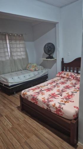 a bedroom with two beds and a window with a fan at Chacara Maua Eventos in Planaltina