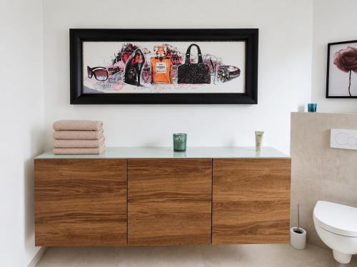 a bathroom with a wooden dresser with a picture on the wall at Cosima in Hohenroth