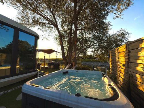 a hot tub in a backyard with a tree at Futuristic Capsule - Private Jacuzzi & Beach access in Wapnica