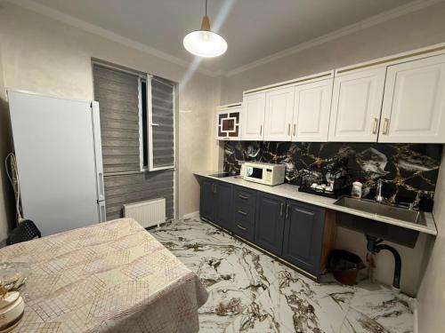 a kitchen with white cabinets and a marble floor at Жилой Комплекс Kemel-UI in Qaskeleng