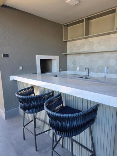 a kitchen with two bar stools and a counter at Apê Calma - 5min Consulado EUA - Garagem in Porto Alegre
