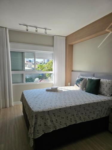 a bedroom with a bed and a large window at Apê Calma - 5min Consulado EUA - Garagem in Porto Alegre