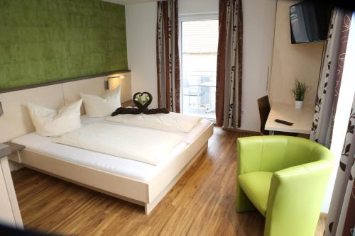 een slaapkamer met een wit bed en een groene stoel bij Goldener Schlüssel mit Gästehaus Sina in Nördlingen