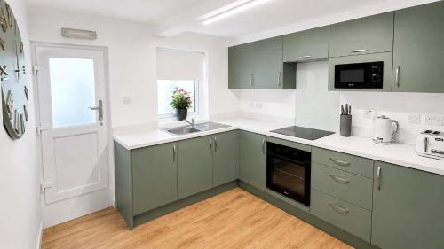 a kitchen with green and white cabinets and a window at Modern Central 3 Bedroom House in Stranraer