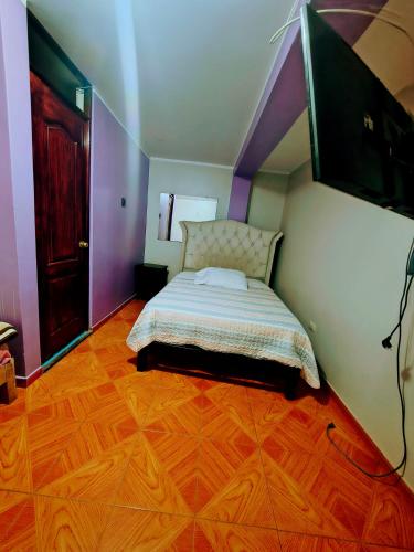 a bedroom with a bed and a tv on the wall at APART TOSCANO Suites in Huancayo