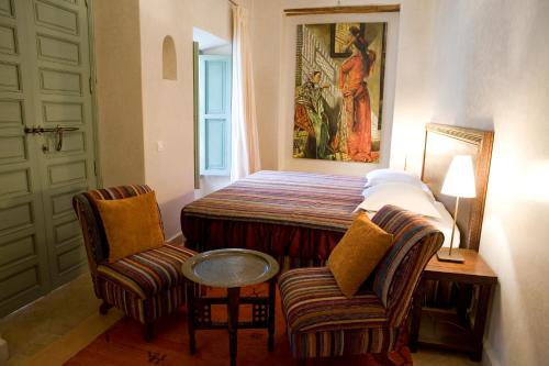 Schlafzimmer mit einem Bett mit 2 Stühlen und einem Tisch in der Unterkunft Riad Les Hibiscus in Marrakesch