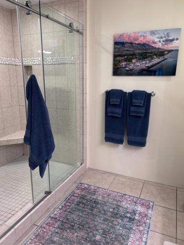 a bathroom with a shower with blue towels and a rug at Kaanapali Royal C102 in Lahaina
